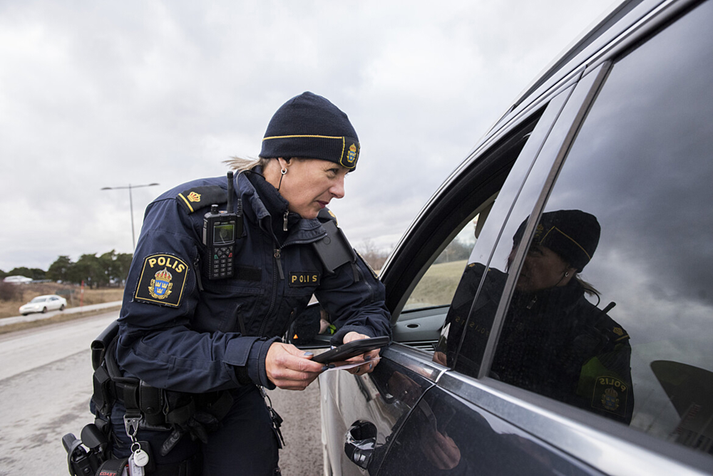 A police officer issues a fine to a car driver.